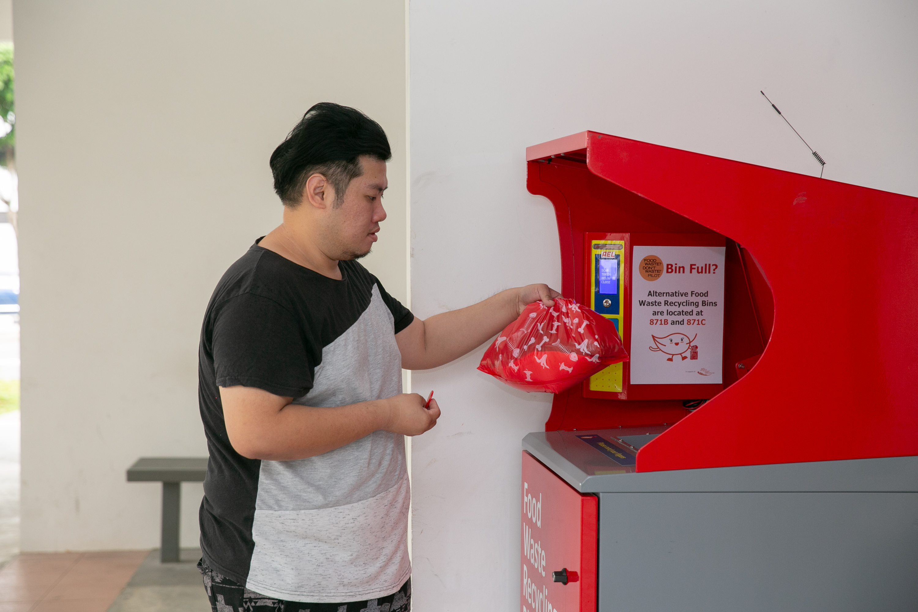 A resident disposes of food waste into a food waste recycling bin